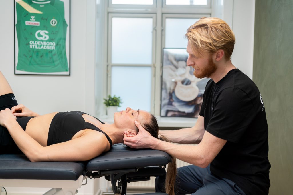Behandler giver massage i nakken på en klient i en klinik for smertelindring og afslapning.