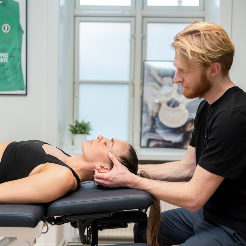 Behandler giver massage i nakken på en klient i en klinik for smertelindring og afslapning.