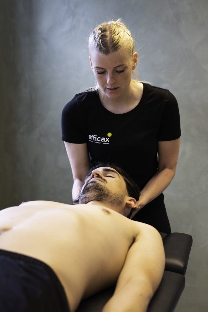 Behandler fra Efficax udfører fysioterapeutisk behandling af en klient, der ligger på en briks, for at lindre ondt i nakke og skulder.