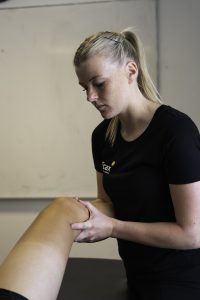 Fysioterapeut fra Efficax undersøger knæ på patient – fokus på behandling af ondt i knæhasen.